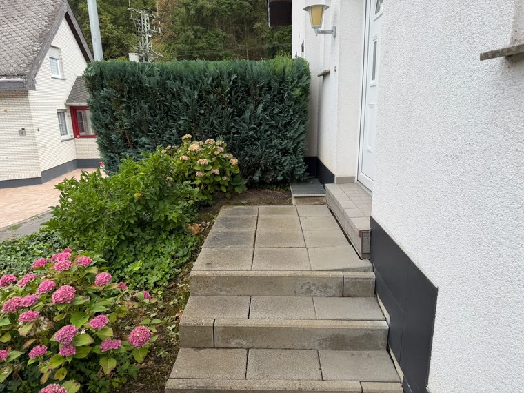 Hauseingang mit freier Treppe und blühenden Hortensien